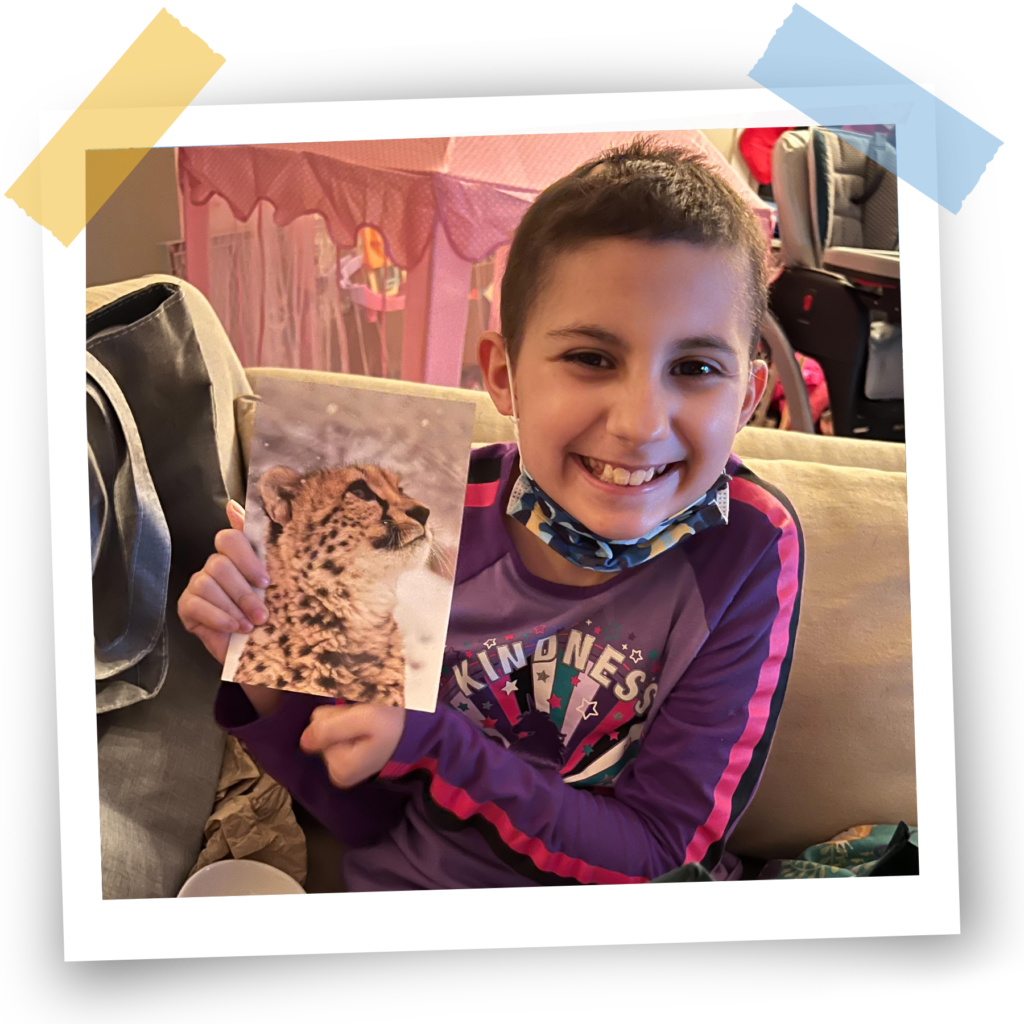 A smiling participant holds up a picture of a cheetah.