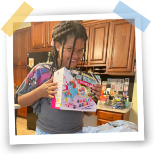 A smiling participant holds up her new paint activity kit.